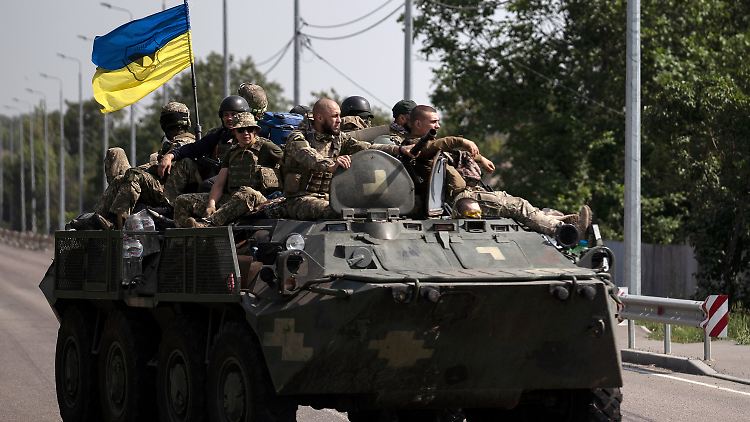Ukrainische Soldaten fahren in der Region Donezk auf einer Straße.