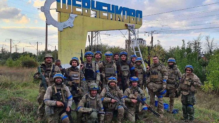 Ukrainische Soldaten posieren am Ortseingang der kürzlich befreiten Siedlung Schewtschenkowe in der Region Charkiw.