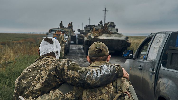 Ein ukrainischer Soldat hilft einem verwundeten Kameraden auf der Straße in dem befreiten Gebiet in der Region Charkiw.