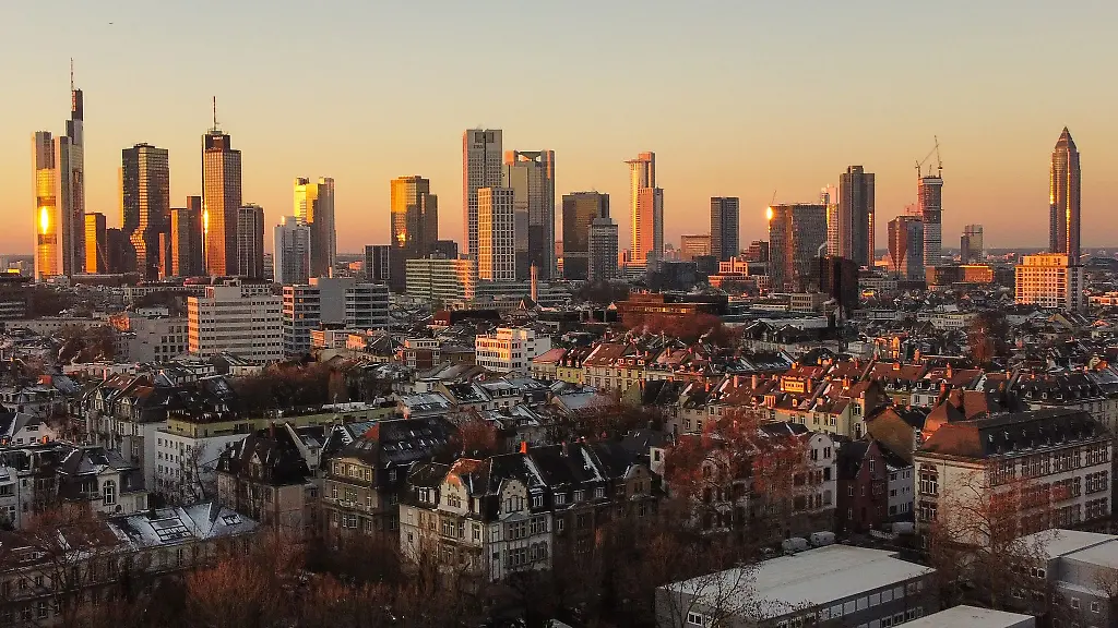 Das-Licht-der-aufgehenden-Sonne-streift-die-Hochhaeuser-der-Skyline-von-Frankfurt