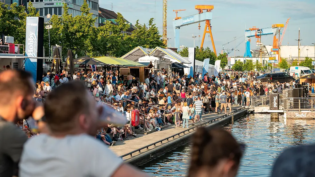 Zahlreiche-Besucher-sitzen-in-der-Abendsonne-auf-einer-Treppe-am-Wall