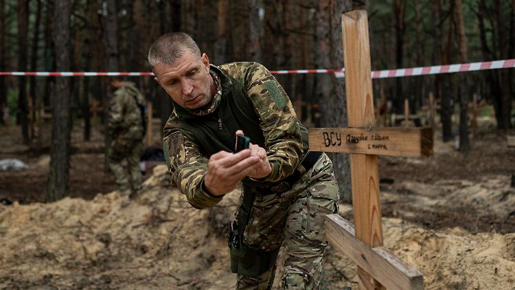 Oleh Kotenko, der ukrainische Vermisstenbeauftragte, filmt mit seinem Smartphone das Grab eines ukrainischen Soldaten.