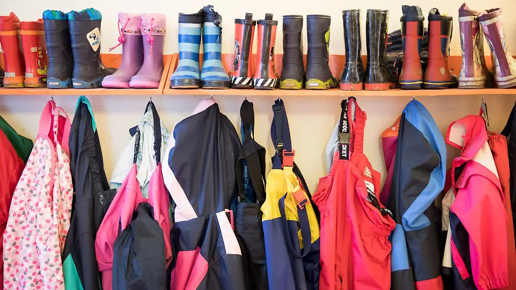 Gummistiefel-und-Regenhosen-von-Kindern-haengen-in-einer-Kita-in-Wedel-an-einem-Regal