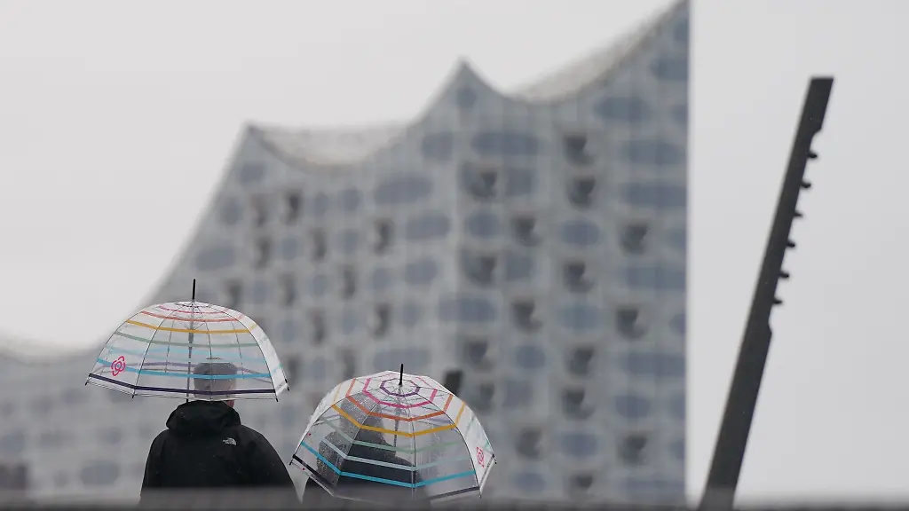 Passanten-gehen-im-stroemenden-Regen-auf-der-Jan-Fedder-Promenade-im-Hamburger-Hafen-spazieren