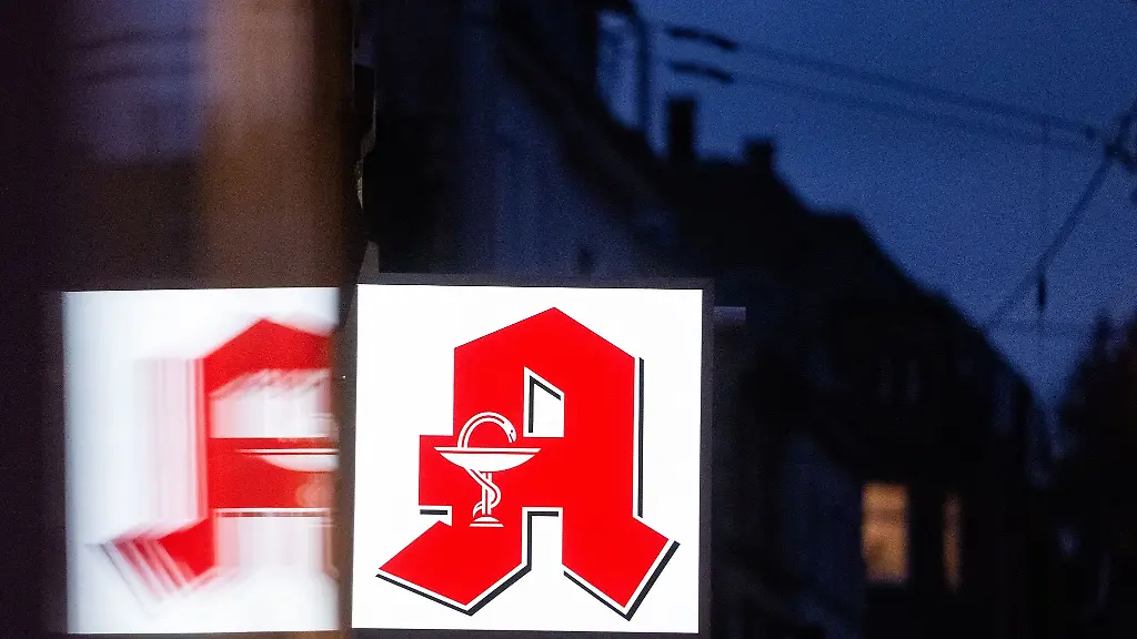 Ein-Apothekenschild-leuchtet-an-der-Fassade-eines-Gebaeudes-in-der-Innenstadt