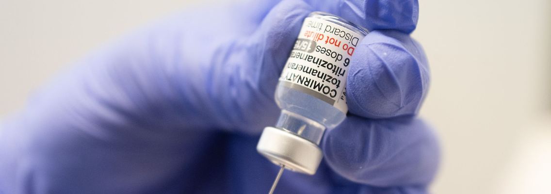 Ein Mitarbeiter zieht eine Spritze mit dem an die Omikron-BA.1-Variante angepassten Impfstoff Comirnaty von Biontech und Pfizer auf.