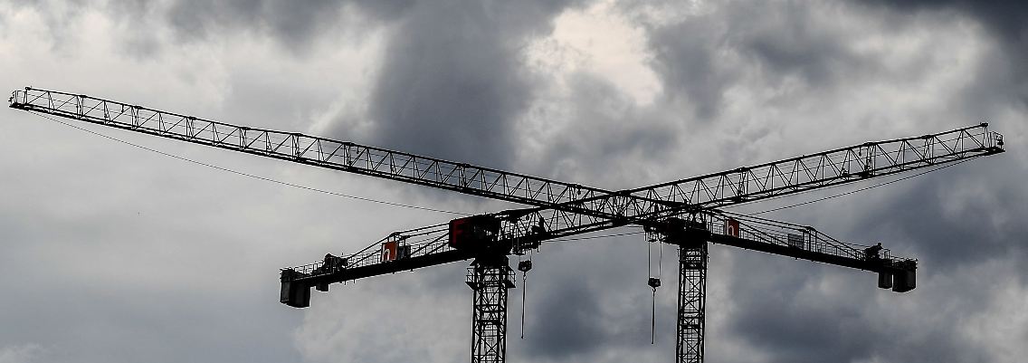 Baukräne vor dunklen Wolken. Fachleuten zufolge wird Deutschland im kommenden Jahr in die Rezession rutschen.