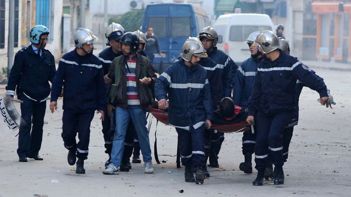 Rettungskräfte und Polizei transportieren einen bei den Unruhen in Tunis verletzten Polizisten ab.