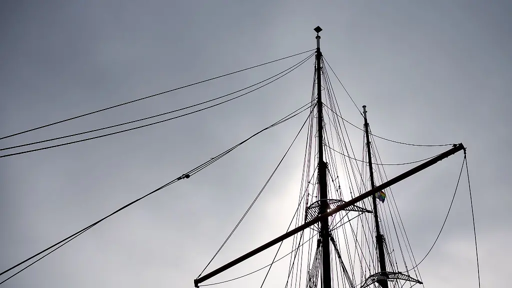 Die-Masten-eines-Segelschiffes-zeichnen-sich-bei-truebem-Wetter-vor-dem-bewoelktem-Himmel-ab