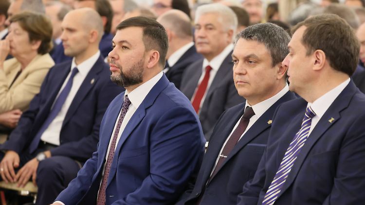 Zu Hause brennt die Hüte: Sichtbar angespannt verfolgt der Donezker Separatistenführer Puschilin (Mitte, links) n Moskau die Annexionsrede des Kremlchefs. 