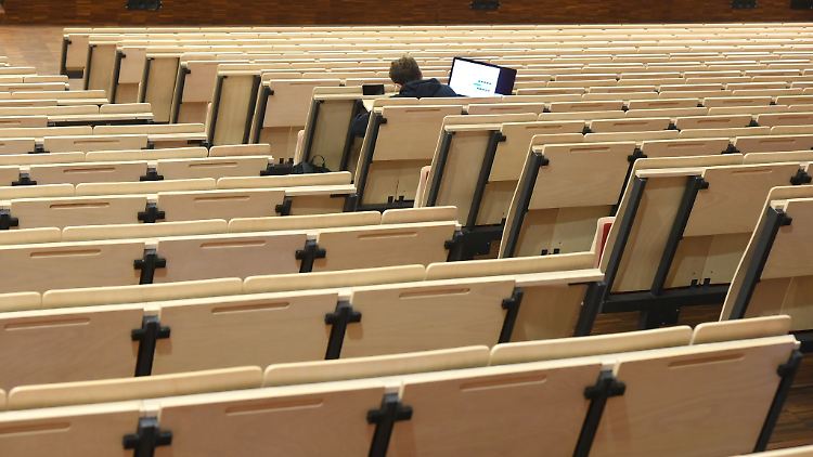 Ein Informatikstudent sitzt bei einer digitalen Vorlesung allein im Auditorium maximum.