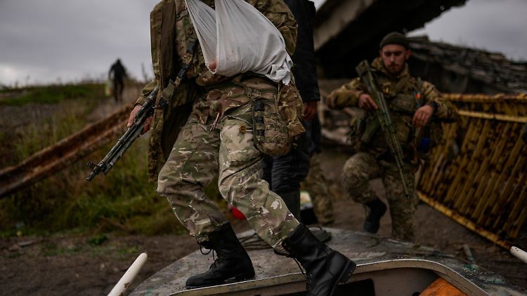 Ukrainische Soldaten steigen über ein Boot nahe einer zerstörten Brücke im Oblast Charkiw.