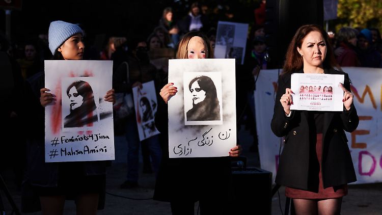 Demonstrantinnen halten in Berlin Schilder in die Höhe, auf der die im Iran getötete Kurdin Jina Mahsa Amini zu sehen ist.