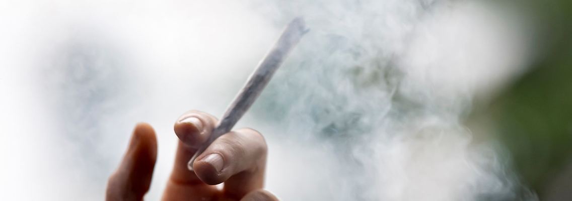 Ein Mann hält einen Joint in der Hand.