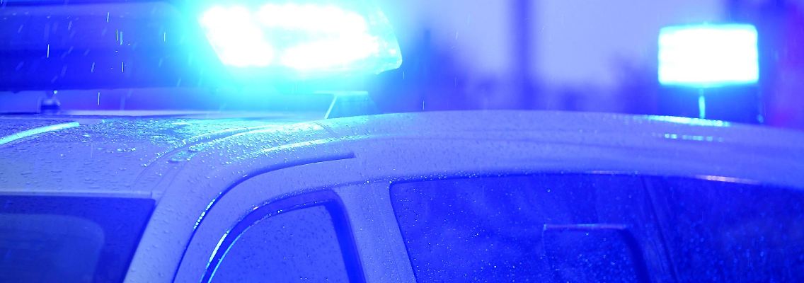Blaulichter leuchten auf dem Dach eines Polizeifahrzeugs.