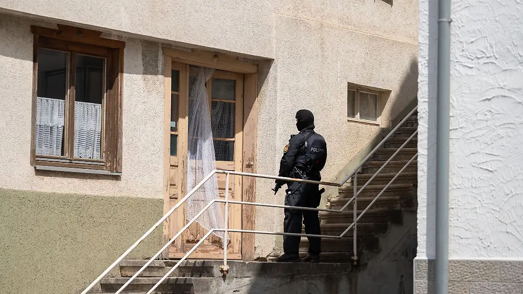 Ein-Polizist-steht-mit-einer-Maschinenpistole-vor-einer-Tuer-in-Althengstett