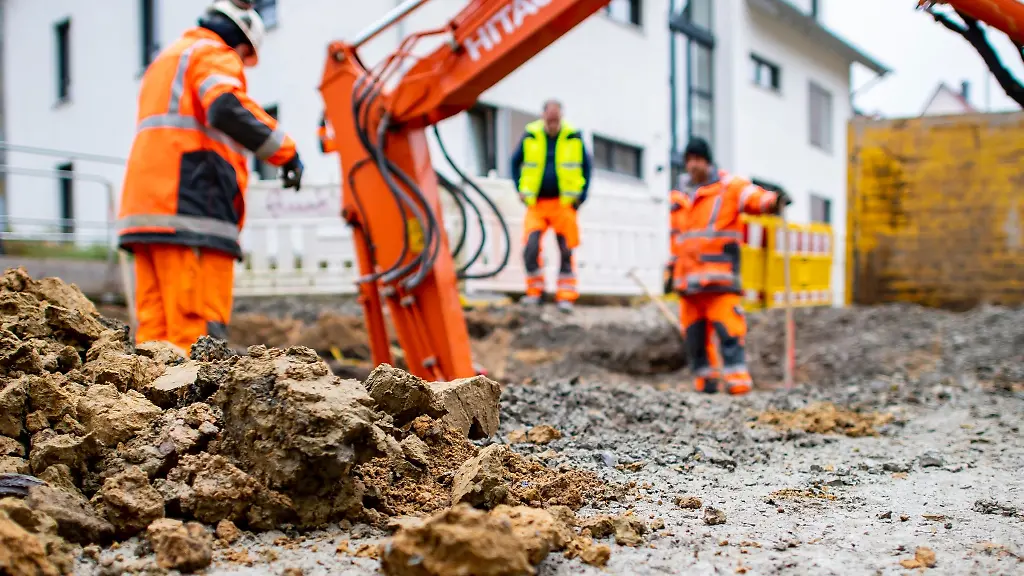 Drei-Bauarbeiter-installieren-in-einer-Baustelle-einen-Hausanschluss-fuer-Regen-und-Schmutzwasser