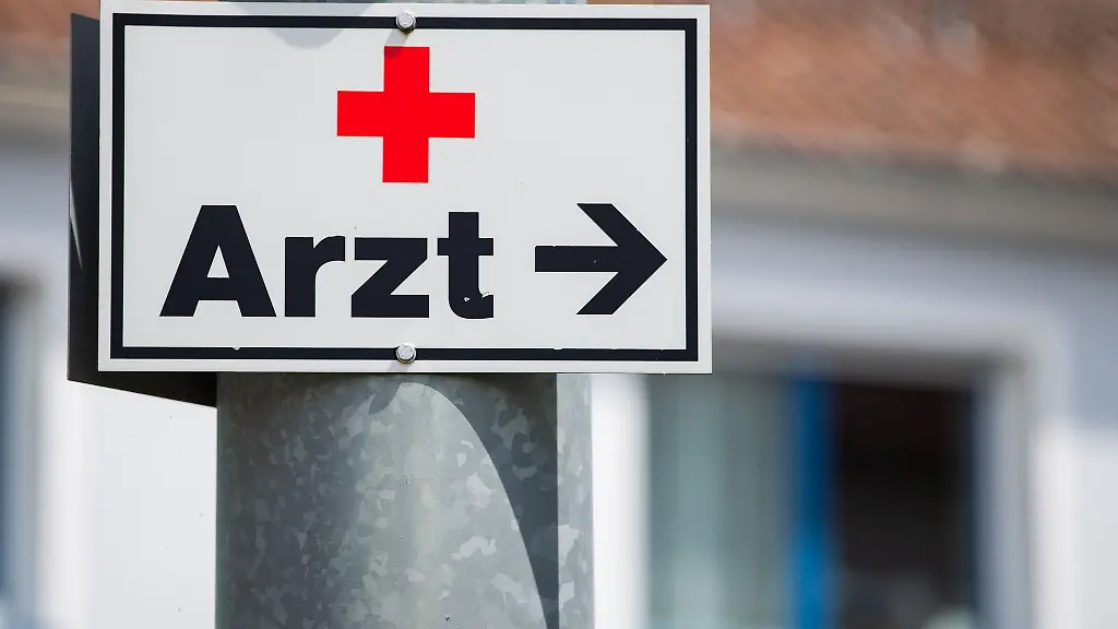 Ein-Schild-mit-der-Aufschrift-Arzt-haengt-an-einer-Strassenlaterne