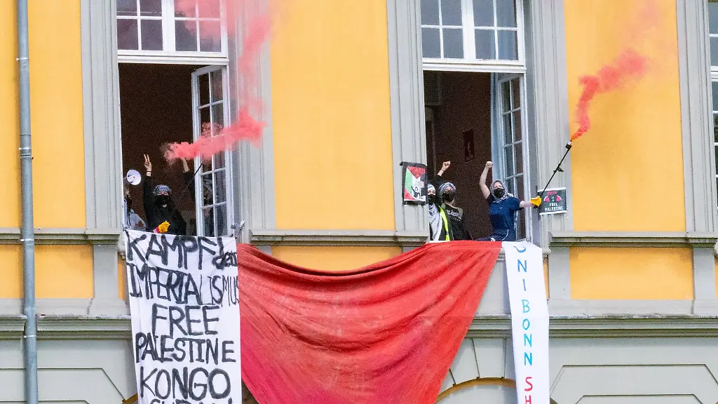 Pro-Palaestinensiche-Demonstranten-halten-Banner-und-Fackeln-aus-den-Fenstern-eines-Hoersaals