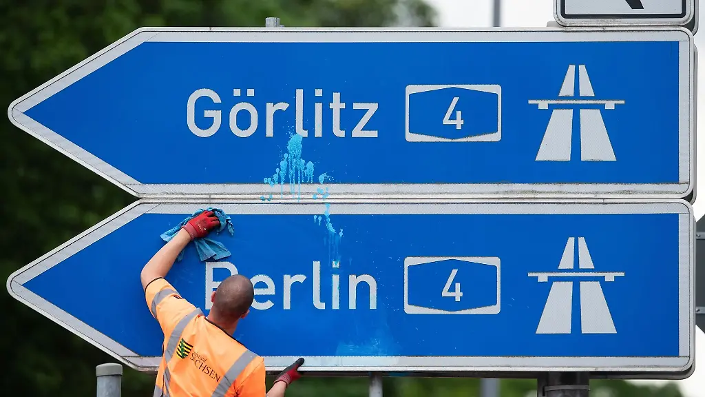 Ein-Mann-reinigt-das-blau-weisse-Schild-der-Autobahnauffahrt-A4-Richtung-Berlin-und-Goerlitz