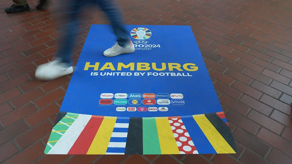 Passanten-gehen-ueber-einen-Euro-2024-Aufkleber-in-der-Wandelhalle-im-Hamburger-Hauptbahnhof