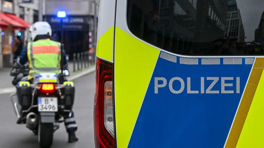 Der-Schriftzug-Polizei-an-einem-Auto-und-ein-Polizist-auf-einem-Motorrad