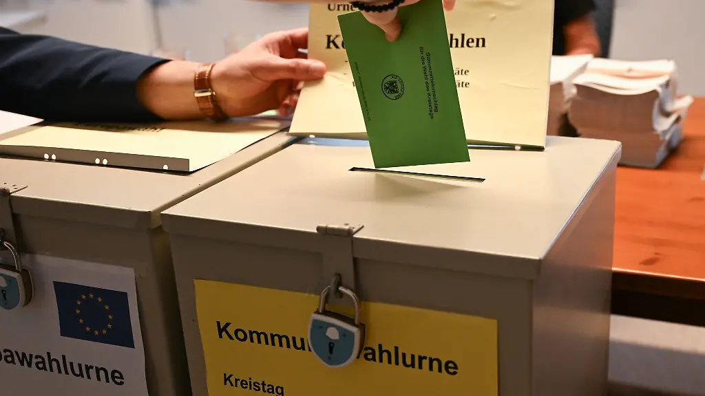 In-einem-Wahllokal-steckt-eine-Waehlerin-ihren-Stimmzettel-fuer-die-Kommunalwahl-in-eine-Wahlurne