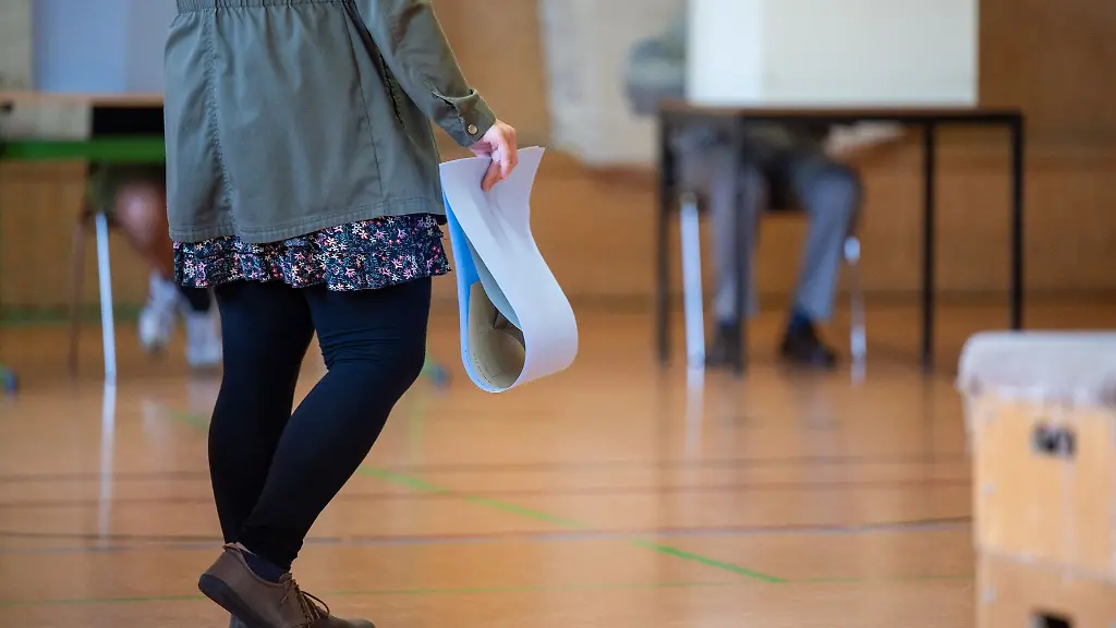 Eine-wahlberechtigte-Frau-wartet-in-einem-Wahllokal-mit-ihren-Stimmzetteln-in-der-Hand-auf-die-Stimmabgabe