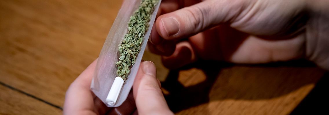 Ein Mann dreht sich einen Joint.