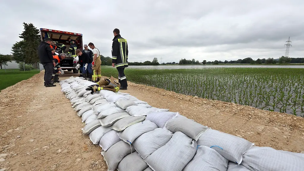 Feuerwehrleute-und-freiwillige-Helfer-befestigen-im-Ortsteil-Auchsesheim-nach-einem-Dammbruch-einen-zweiten-Damm-mit-Sandsaecken-um-das-Hochwasser-der-Zusam-zu-stoppen