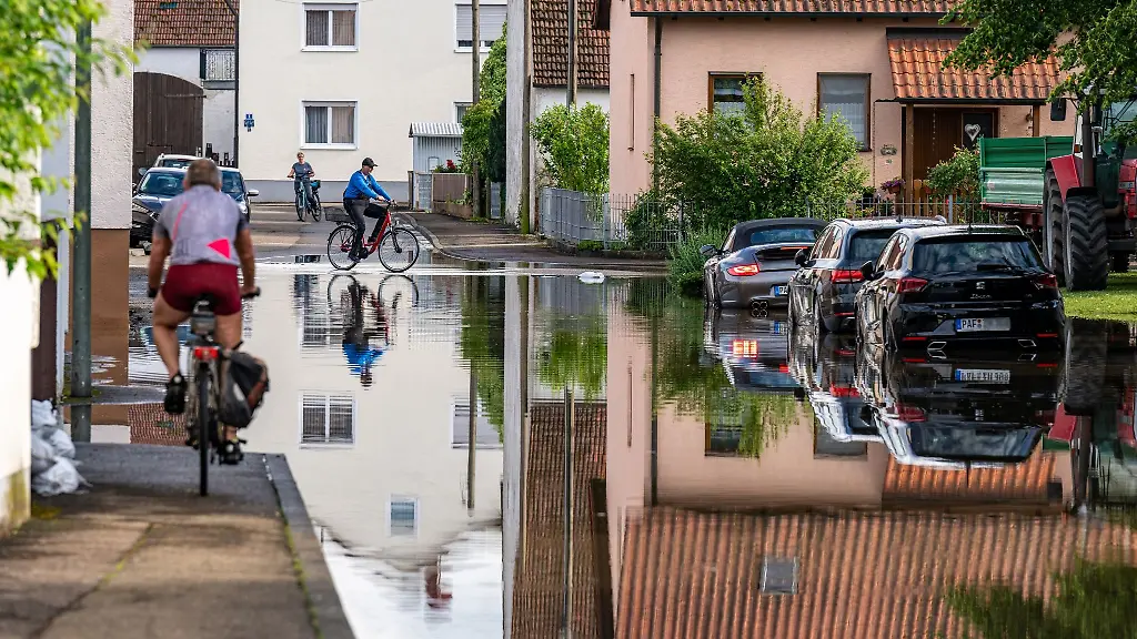 Radler-fahren-durch-eine-ueberflutete-Strasse