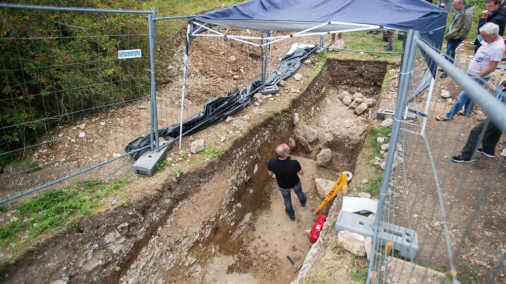 Gerd-Stegmaier-M-wissenschaftlicher-Referent-fuer-die-Region-am-Heidengraben-steht-in-der-Ausgrabungsstaette-am-Wallschnitt-der-Befestigungsanlage-auf-der-Bassgeige-im-Heidengraben
