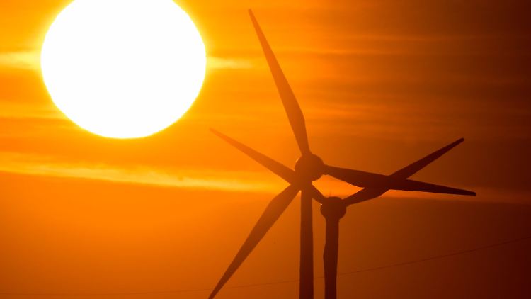Die Sonne geht hinter Windrädern auf.