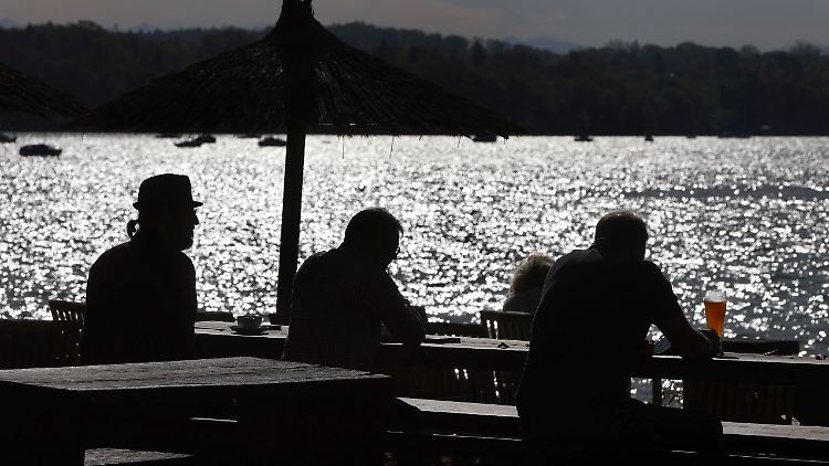 Menschen genießen in einem herbstlichen Biergarten in Stegen am Ammersee die milden Temperaturen.