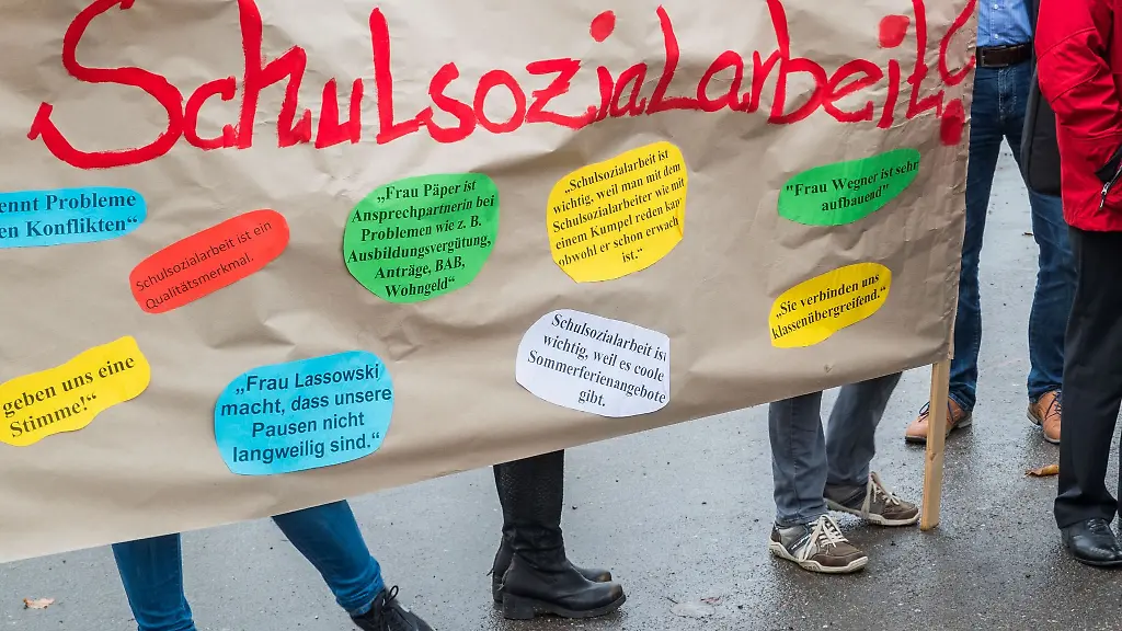 Teilnehmer-einer-Demonstration-halten-ein-Plakat-mit-der-Aufschrift-Schulsozialarbeit-hoch