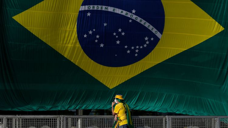 Ein Anhänger des abgewählten Präsidenten Bolsonaro steht neben einer brasilianischen Flagge.