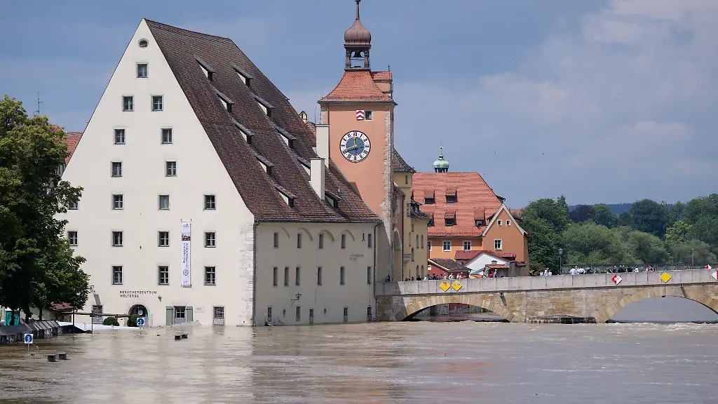 Menschen-stehen-in-der-Altstadt-auf-der-Steinernen-Bruecke-und-schauen-sich-das-Hochwasser-an