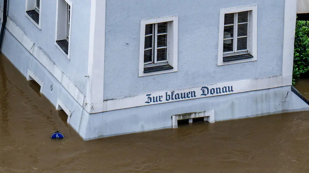Ein-Haus-mit-dem-Schriftzug-Zur-blauen-Donau-steht-im-Hochwasser-der-Donau
