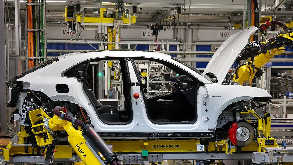 Industrieroboter-arbeiten-an-einem-vollelektrischen-Porsche-Macan-nach-der-Hochzeit-der-Verbindung-von-Fahrwerk-und-Motor-mit-der-Karosse-im-Werk-Leipzig