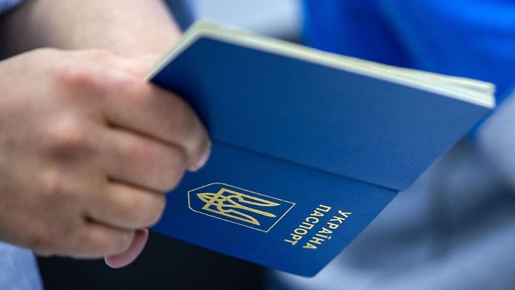 Ein Mann hält einen ukrainischen Reisepass in der Hand.