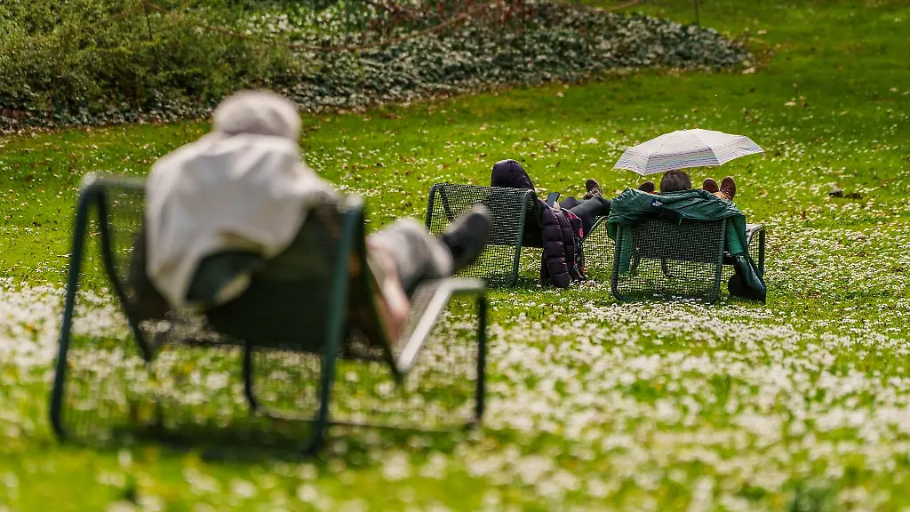Ein-Besucher-des-Palmengartens-schuetzt-sich-auf-der-Liegewiese-vor-der-Sonne