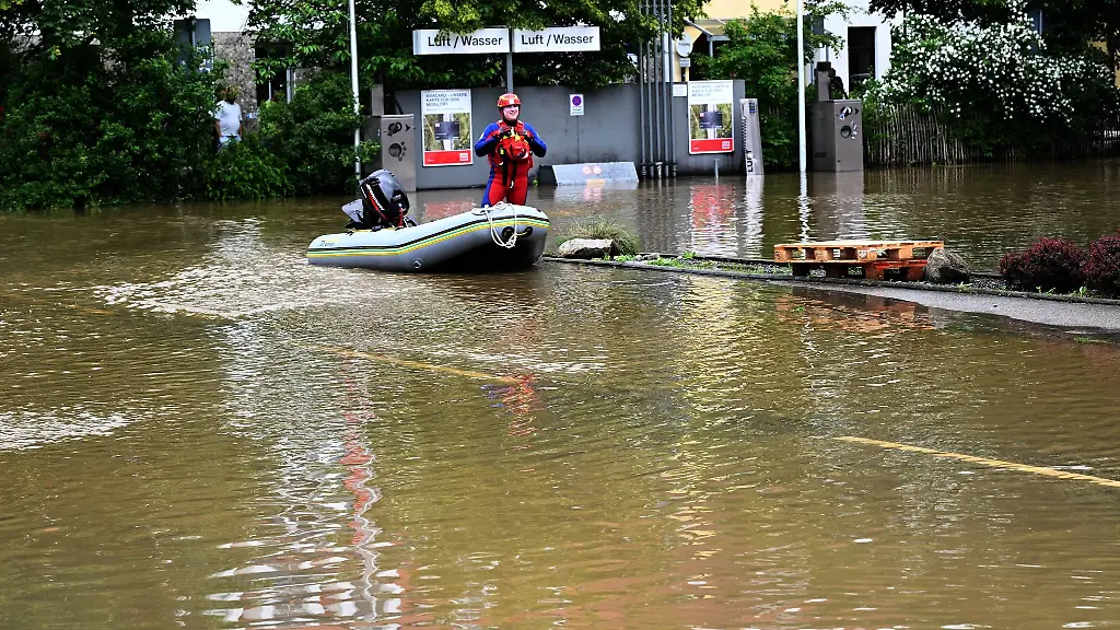 Ein-Helfer-kommt-mit-dem-Schlauchboot-zu-einer-ueberschwemmten-Tankstelle-in-Allershausen
