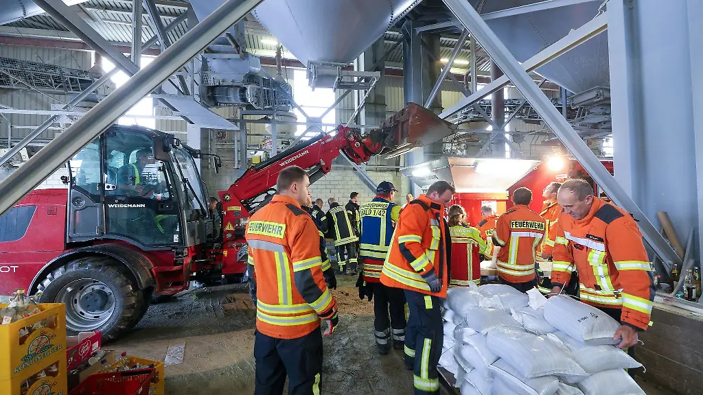 Einsatzkraefte-der-Feuerwehr-fuellen-Sandsaecke-ab