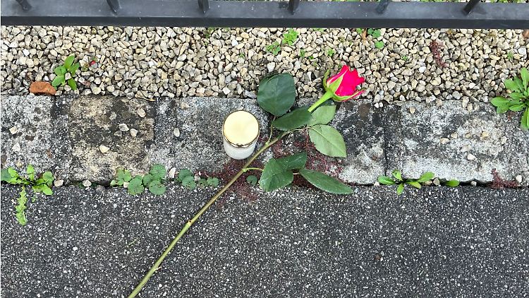 Eine Rose an einem der Tatorte.  An einem anderen Ort haben Menschen eine Handvoll Kerzen aufgestellt. 