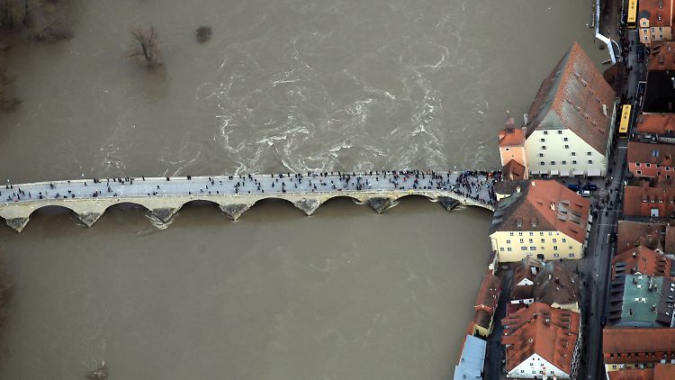 Schaulustige betrachten das Hochwasser auf der Steinernen Brücke in Regensburg.
