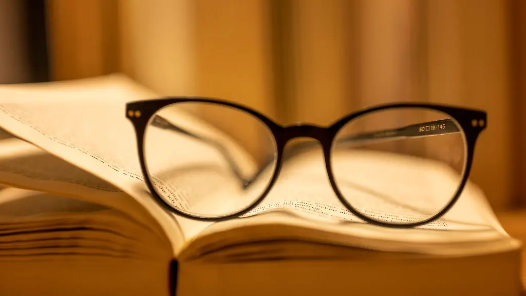Eine-Lesebrille-liegt-auf-einem-geoeffneten-Papierbuch