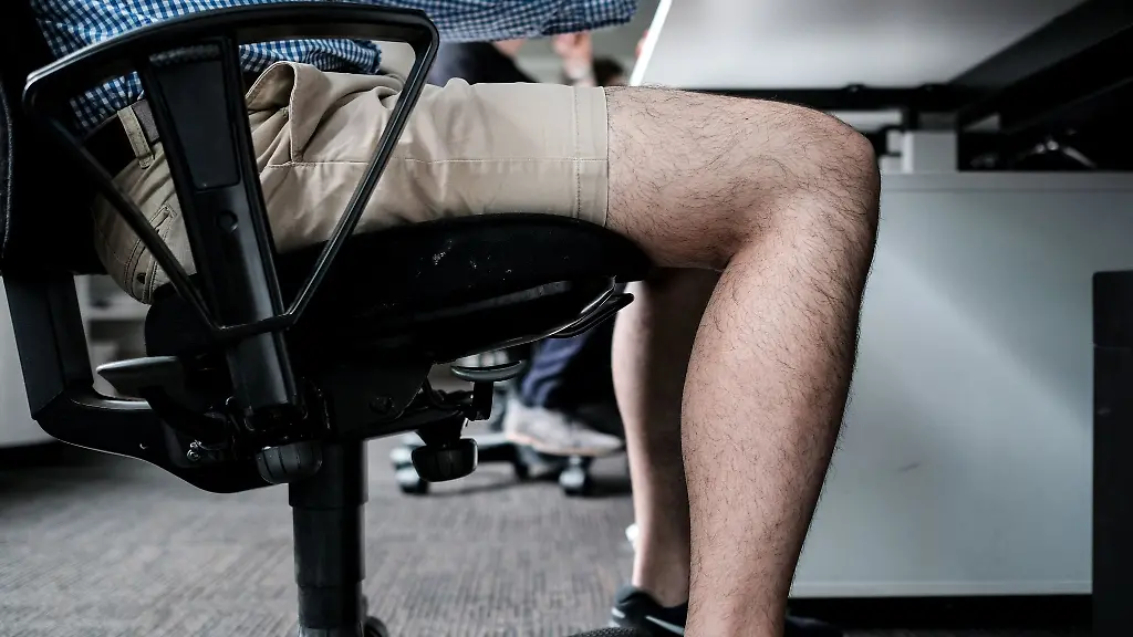 Ein-Mann-sitzt-mit-kurzer-Hose-an-seinem-Arbeitsplatz