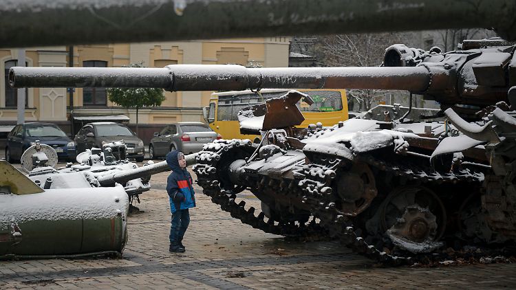 Ein Kind betrachtet eine Ausstellung von zerstörten russischen Panzern und gepanzerten Fahrzeugen nach Schneefall.