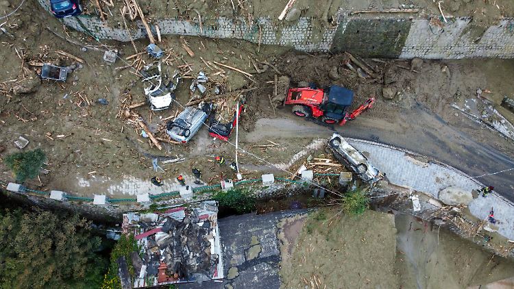 Über den Ort verstreut lagen die Überreste von zerstörten Fahrzeugen, die Geröll und Schlamm zerdrückt hatten. Bagger versuchten, Haus- und Geschäftseingänge sowie Autos freizuräumen.