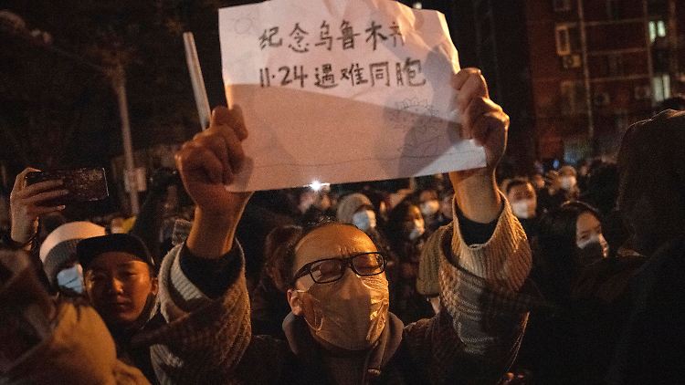 Nicht alle Schilder sind weiß: Erinnert euch an die Landsleute, die am 24.11. in Ürümqi starben", steht auf diesem Zettel, das ein Demonstrant in Peking hochhält.